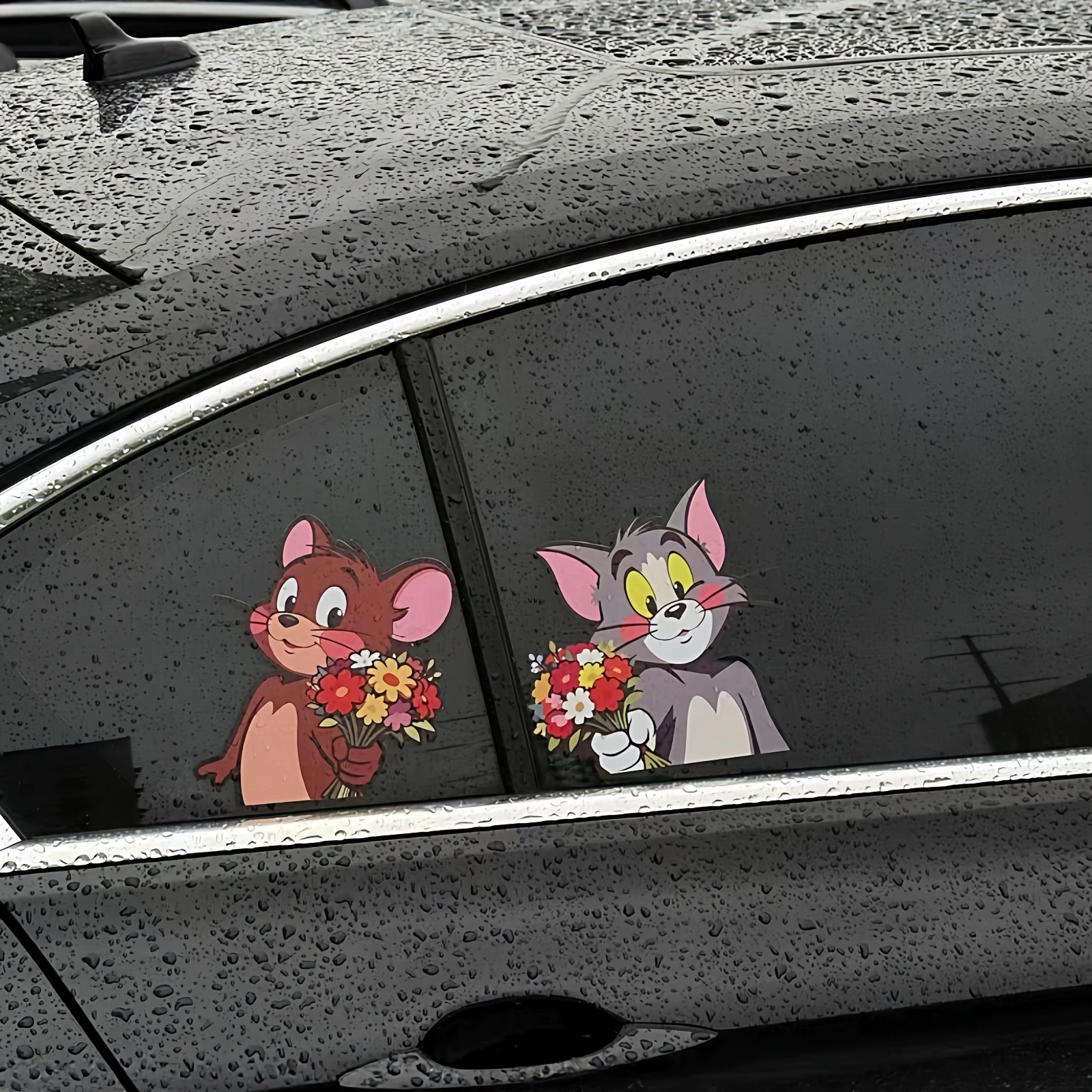 Waterproof Tom and Jerry car decals on a rainy side window for all-weather durability.